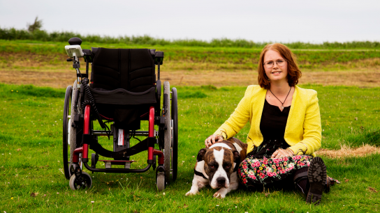 A woman with a rare disease and her dog, next to her wheelchair